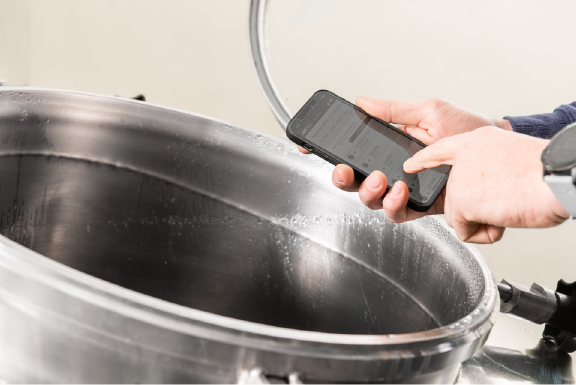 Hand mit Smartphone und MINGLECONTROL App über Sudkessel